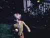 Automne: fillette avec pomme dans les mains. Enfants s'amusent à côté des fleurs. Plusieurs pommes par terre.