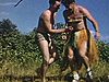 Monsieur en jupe de paille hawaïenne et haut de bikini. Déguisement. Extérieur, danse du ventre - rigolo - Tous rient scène très drôle Un homme danse la jungle