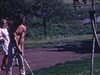 Homme torse nu sur le gazon, sur le bord du chemin, pratique son coup d'envoi au golf. Femme avec caddie, hommes pratiquent - gros plan bâtons qui frappent