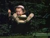 Maman fait balancer bébé sur balanôire publique (beau plan)
