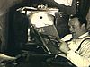 Deux hommes devant la radio qu'ils synthonisent, lisent un magazine «Life» (avec drapeau américain à la une), très beau plan des années 30, page de magazine sur les avions militaires