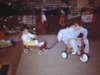 Noël: deux frères font un petit train avec un tricyle, une voiturette et un cheval, et ils tournent dans le salon