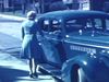Madame ouvre la portière de l'auto, entre et sort, mise en scène pour le caméraman. Dame ouvre la portière et 4 enfants en sortent. Famille pose devant la très belle automobile bleue 1942