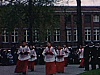 Fête Dieu procession dans les rues, arrive à l'église, enfants de choeur suivis des Chevaliers de Colomb en costume qui portent le Sacré Coeur (croix dorée) avec baldaquin