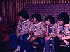 Les scouts chantent des chansons de Noël tous ensemble assis sur des divans / son : les scouts chanent Le Renne au nez rouge, Frère Jacques en canon.