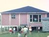 Chalet sur pilotis, enfants sur le terrain, un homme les place en ligne et donne le départ pour une course, ils avancent vers la caméra, jeux d’été