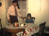Repas de Noël, famille s’installe à table pendant que la mère surveille le repas, père Noël arrive salue la caméra puis enlève sa barbe et sa tuque, télé allumée dans la cuisine, puis famille discute au salon - années 70