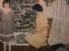 Party de Noël en famille, gens assis sur le divan près de l’arbre de Noël, petite fille fait des pirouettes - gymnastique