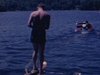 Un homme fait du ski nautique,part du quai. Un oiseau sort d’une cabane et s’envole