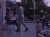 Adultes sur la terrasse du chalet, boivent une bière assis sur des chaises pliantes au soleil, bref plan à l’intérieur des enfants sur les divans. un couple d’adolescents marche vers la caméra