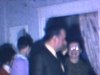 Un homme donne la bénédiction paternelle (jour de l’An) à la cuisine, petite maison, party de Noël, table et buffet, invités se promènent, enfants regardent les cadeaux emballés