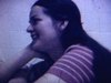 Gros plan d’une jeune femme qui sourit à la caméra, elle semble être dans une salle de classe - école - cégep 1972