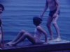 Des enfants jouent sur le quai d’un lac ils sautent à l’eau, font des jeux d’équilibre, un homme part en chaloupe à moteur, les enfants jouent avec des matelats flottants