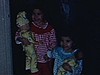 Deux petites filles en pyjama au salon, elles saluent la caméra assises près de leurs cadeaux emballés sous le sapin de Noel