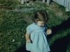 Petite fille dans la cour de la maison, elle joue dans le gazon et porte une jolie robe