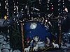 Crèche sous le sapin de Noel, petites filles jouent à la poupée, leurs cadeaux, elles portent des tabliers roses (rôle féminin) et déballent un gros cadeau à deux, enfants jouent avec leurs cadeaux