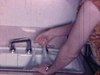 Femme joue avec un sac en plastique rempli d’eau au-dessus du lavabo dans la cuisine - étrange, bizarre (1962)