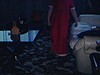 Une petite fille en jaquette parade pour la caméra au salon, elle lèche les bâtons d'un batteur électrique à la cuisine, une femme est assise sur le divan du salon et est éblouie par la lumière de la caméra