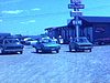 Stationnement d’un restaurant, enseigne«Épicerie, bière, restaurant», les gens entrent dans les autos et partent, autos stationnées sur l’herbe près de la plage