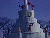 Sculpture de glace d’un faux gros château avec un 10 sur le dessus, un couple pose à la base de la sculpture - carnaval de Québec 1966