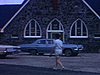 Une femme marche dans le stationnement d’une église en pierres vers une automobile à la porte et...