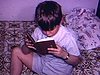 Petit garçon assis sur lit et il lit la Bible, sa mère la lui enlève et il s’assoit avec un vieux toutou dans les bras, il se frotte les yeux, se couche, sa mère vient le border, il met sa tête sur l’oreiller, tableau «FIN»
