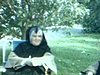 Deux religieuses assises sur des chaises de jardin sous un pommier. Une soeur voilée cueille une pomme et la mange. Une flllette et un garçon caché dans le feuillage du pommier cueilles des pommes et en mangent