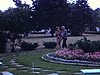 Un homme et une femme marchent dans un jardin près d’une statue - à identifier