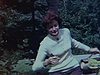 Une femme assise sur un rocher, elle sourit à la caméra