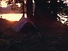 Terrain de camping avec quelques tentes au bord de l’eau, lever du soleil, les gens dorment puis se réveillent et se préparent le matin