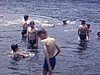 Plusieurs garçons et une femme se baignent dans un lac et jouent sur une plate-forme flottante