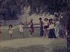 Dans un parc, une fête d’enfants, une femme déguisée en diseuse de bonne aventure, des enfants déguisés, des ballons dans les arbres