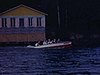 Famille dans une chaloupe à moteur salue la caméra en avançant sur le lac