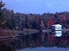Paysage d’automne, un chalet au bord d’un lac entouré d’arbres colorés