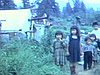 Des enfants autochtones dans le bois, quelques cabanes, les enfants regardent la caméra - amérindiens