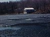 Famille dans une chaloupe, un adolescent rame, il reste de la glace sur le lac; trois garçons posent pour la caméra, puis un ado rame