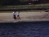Deux femmes se trempent les pieds dans l’eau sur la plage, images prises d’une chaloupe, reflets de soleil sur l’eau