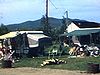 Terrain de camping, tentes-roulottes, famille autour d’une table à pique-nique, les enfants s’amusent dans un kart de golf