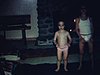 Un petit garçon de 8 ans et une petite fille de 4 ans dansent devant le feu de foyer, un homme et une femme les regardent, une femme vient les rejoindre