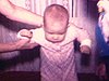 Une bébé est coucher dans sa bassinette, gros plan sur le visage d'un petit garçon qui semble pleurer, une mère essai de faire marcher son bébé, elle le prend dans ses bras
