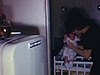 Maman couche bébé dans la bassinette, un homme est à ses côtés. Deux petits garçons dansent devant la caméra, maman derrière avec son bébé - années 80