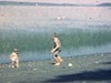 Famille sur des serviettes de plage près d’un lac, les enfants marchent sur des roches, jouent. les mères se reposent