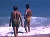 Des hommes se baignent dans les vagues en Floride, plusieurs baigneurs, des touristes sur la plage se prélassent au soleil