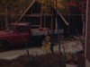 Automobile stationnée sur le terrain d’un chalet, l’automne, des femmes regardent le paysage aux feuilles colorées au bord du lac, un homme sur du chalet en construction - 1978