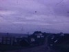 Filmé d’une automobile en marche, quelques villages de la Gaspésie, journée sombre pluvieuse, bateaux de pêcheurs