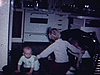 Deux enfants à la cuisine avec un chien berger allemand, le petit garçon se lève et joue avec le chien, le bébé rampe par terre, la mère vient le prendre dans ses bras quand le chien approche - 1970