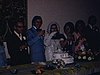 Réception après le mariage, les mariés s’embrassent (baiser)  à la table d’honneur, tables des invités, mode années 70
