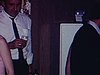 Anniversaire d’un homme, il souffle les bougies sur son gâteau, la famille autour, les invités mangent du gâteau, puis ils font un jeu: l’homme a une carotte attachée au derrière et il essaie de la faire entrer dans un vase par terre 