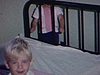Une petite fille fait son lit, son petit frère est debout à côté et regarde la caméra en souriant 1963 quotidien