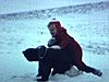 Enfants emmitouflés jouent dans la neige, ils se poussent et courent, une femme sort de l’automobile suivie des enfants qui restent dehors et pelletent de la neige 1963